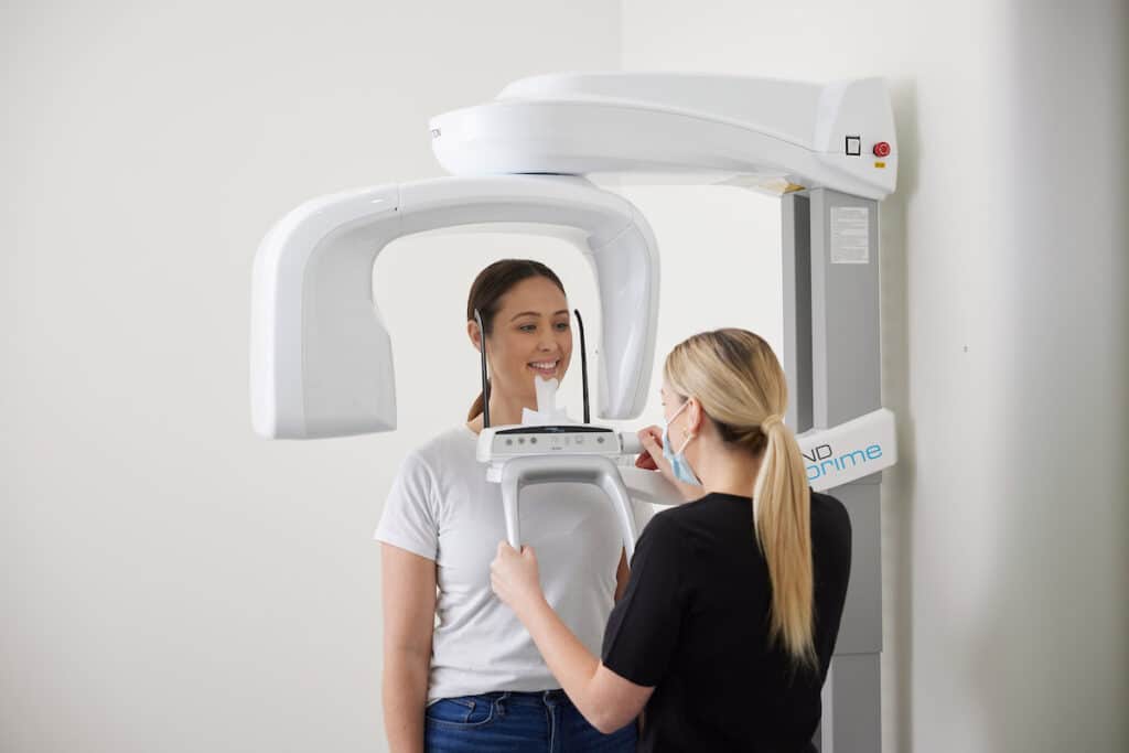 Patient undergoing a digital panoramic dental X-ray during an orthodontic consultation to assess teeth, jaw alignment, and treatment planning.